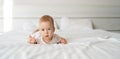 serious white caucasian baby boy with blue eyes six months old lying on the bed and looking at the camera. straight view Royalty Free Stock Photo