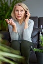 Serious woman attending a phone call sitting on a sofa in the living room at home. Royalty Free Stock Photo