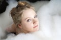 Serious woman enjoys the bath-foam in the bathtub. Royalty Free Stock Photo
