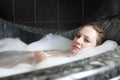 Serious woman enjoys the bath-foam in the bathtub. Royalty Free Stock Photo