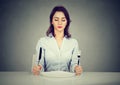 Serious woman with fork and knife sitting at table with empty plate Royalty Free Stock Photo