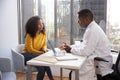 Serious Woman Having Consultation With Male Doctor In Hospital Office Royalty Free Stock Photo
