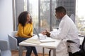 Serious Woman Having Consultation With Male Doctor In Hospital Office