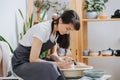 Serious woman shaping clay tableware on a pottery wheel in her private workshop