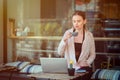 Serious woman sitting at cafe terrace holding coffee mug working on laptop Royalty Free Stock Photo