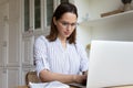 Serious woman wear glasses working on computer at home office