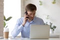 Serious worker talking by phone looking at laptop screen Royalty Free Stock Photo