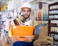 Serious workman holding basket with picked tools