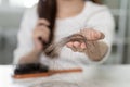 Serious, worried asian young woman, girl holding brush, show her comb, hairbrush with long loss hair problem after brushing, hair Royalty Free Stock Photo