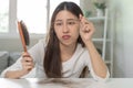 Serious, worried asian young woman, girl holding brush, show her comb, hairbrush with long loss hair problem after brushing, hair Royalty Free Stock Photo