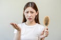 Serious, worried asian young woman, girl holding comb, show her hairbrush with long loss hair problem after brushing, hair fall Royalty Free Stock Photo