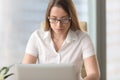 Serious worried businesswoman working on laptop, looking at scre