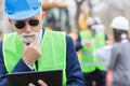 Serious, worried, senior gray haired engineer or businessman working on a tablet on construction site Royalty Free Stock Photo