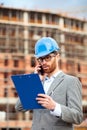 Worried young businessman or architect standing on a construction site and talking on the phone Royalty Free Stock Photo