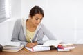 Serious, writing and student studying in college, learning and work on school project at desk. Reading, books and woman Royalty Free Stock Photo