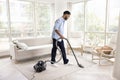Serious young African homeowner man vacuuming floor in living room Royalty Free Stock Photo