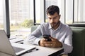 Serious young Arab businessman typing on smartphone on job chat