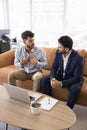 Serious young Arab employee man talking to Indian colleague