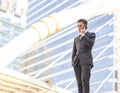 Young Asian business man in black suit  talking on mobile phone outdoor with city buiding background Royalty Free Stock Photo