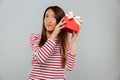 Serious young asian lady standing isolated holding gift.