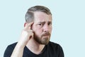 Serious young bearded man touches his forehead with his finger. Focuses attention on the problem. Isolated portrait on a pastel Royalty Free Stock Photo