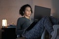 Serious black brazilian student with curly afro hair having online classes on notebook sitting on chair. Inside the house in