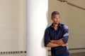 Serious young black man leaning against wall with arms crossed Royalty Free Stock Photo