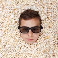 Serious young boy in stereo glasses looking out of popcorn Royalty Free Stock Photo