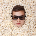 Serious young boy in stereo glasses looking out of popcorn Royalty Free Stock Photo