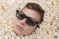 Serious young boy in stereo glasses looking out of popcorn Royalty Free Stock Photo