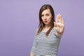 Serious young brunette woman girl in casual striped clothes posing isolated on violet purple background studio portrait Royalty Free Stock Photo