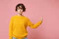 Serious young brunette woman girl in yellow sweater posing isolated on pastel pink wall background studio portrait Royalty Free Stock Photo