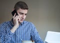 Serious young business man speaking on phone, checking data on screen Royalty Free Stock Photo