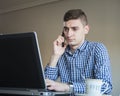 Serious young business man speaking on phone, checking data on screen Royalty Free Stock Photo