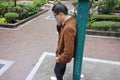 Serious young business man in suit talking on the mobile phone while leaning a pole at the outdoor park. Royalty Free Stock Photo