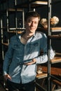 Serious young business man using digital tablet while standing near shelves in office room. Royalty Free Stock Photo