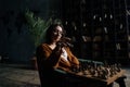 Serious young business woman in elegant eyeglasses making chess move sitting on armchair in dark library room, on Royalty Free Stock Photo