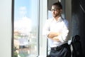 Serious young businessman keeping arms crossed and looking away while standing near the window Royalty Free Stock Photo