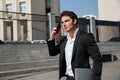 Serious young businessman walking outdoors talking by phone. Royalty Free Stock Photo