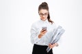 Serious young businesswoman in glasses holding folders and using smartphone Royalty Free Stock Photo