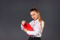 Serious young businesswoman with a red folder on a gray background posing. Side white space. Royalty Free Stock Photo