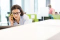 Serious young businesswoman talking on mobile phone in office Royalty Free Stock Photo