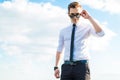 Serious young busunessman in white shirt, tie and sunglasses sta