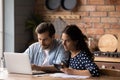 Serious young couple calculating household bills in kitchen, planning budget