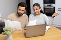 Serious young couple study documents together, have serious looks, dressed in casual wear, plan their budget, pose in