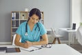 Serious young doctor sitting at desk and completing information in patient medical history Royalty Free Stock Photo