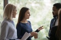 Serious young employee talking to diverse coworkers