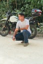 Serious young ethnic biker in casual clothes near motorcycle