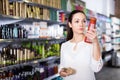 Serious young female choosing hair care products at cosmetics showroom Royalty Free Stock Photo