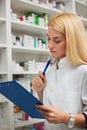 Serious young female pharmacist holding a clipboard